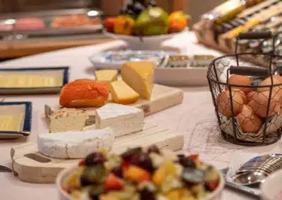 Rijkelijk ontbijtbuffet in Hotel Auberge l'Entrecôte met kazen, fruit, honing en kaarsverlichting.